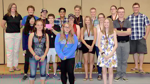 Eine Gruppe von Schülerinnen und Schülern mit Erwachsenen steht vor einer Holzvertäfelung in der Clearwater Secondary School.