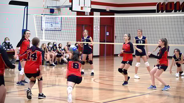 Schülerinnen der Clearwater Secondary School spielen Volleyball auf einem Basketballfeld mit sichtbarer Anzeigetafel.
