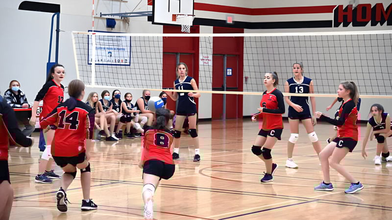 Schülerinnen der Clearwater Secondary School spielen Volleyball auf einem Basketballfeld mit sichtbarer Anzeigetafel.