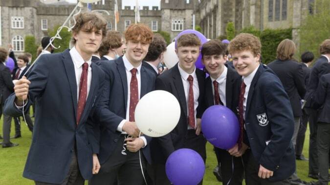 Schüler des Clongowes Wood College feiern auf dem Campus mit Luftballons vor historischen Gebäuden.