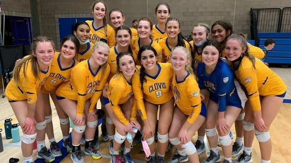 Schülerinnen der Clovis High School in gelb-blauen Uniformen posieren gemeinsam in der Sporthalle.