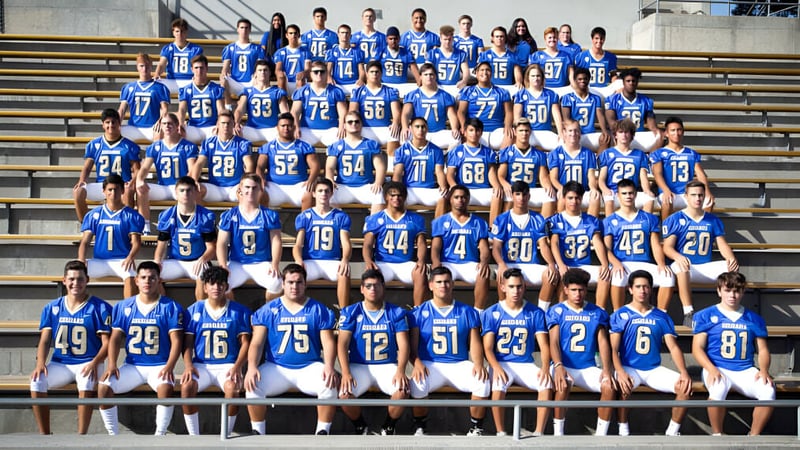 Eine große Gruppe von Schülerinnen und Schülern in blauen Uniformen steht auf den Tribünen im Stadion des Clovis Unified School District.