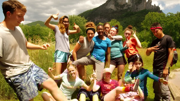 Eine Gruppe von Schülern der Cnoc Mhuire Secondary School versammelt sich im Freien vor einer Berglandschaft mit üppiger Vegetation.