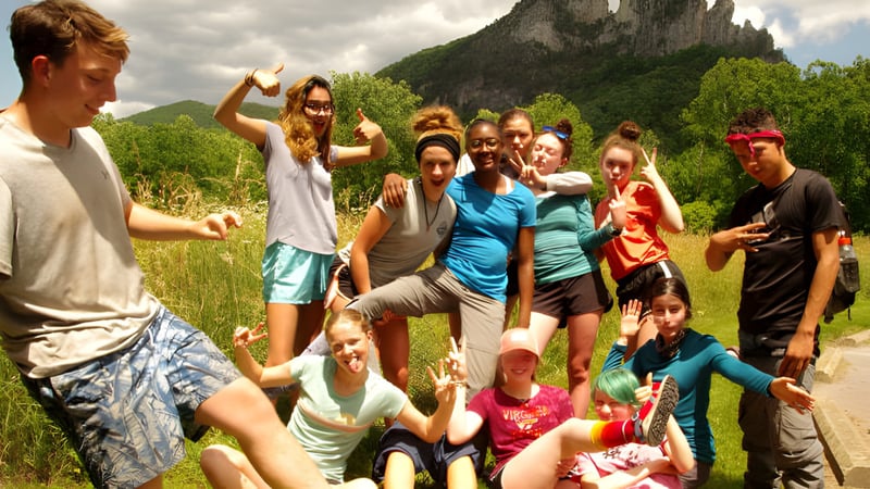 Eine Gruppe von Schülern der Cnoc Mhuire Secondary School versammelt sich im Freien vor einer Berglandschaft mit üppiger Vegetation.