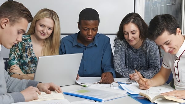 Schüler der Cnoc Mhuire Secondary School arbeiten gemeinsam an einem Projekt mit Laptop und Schulbüchern.