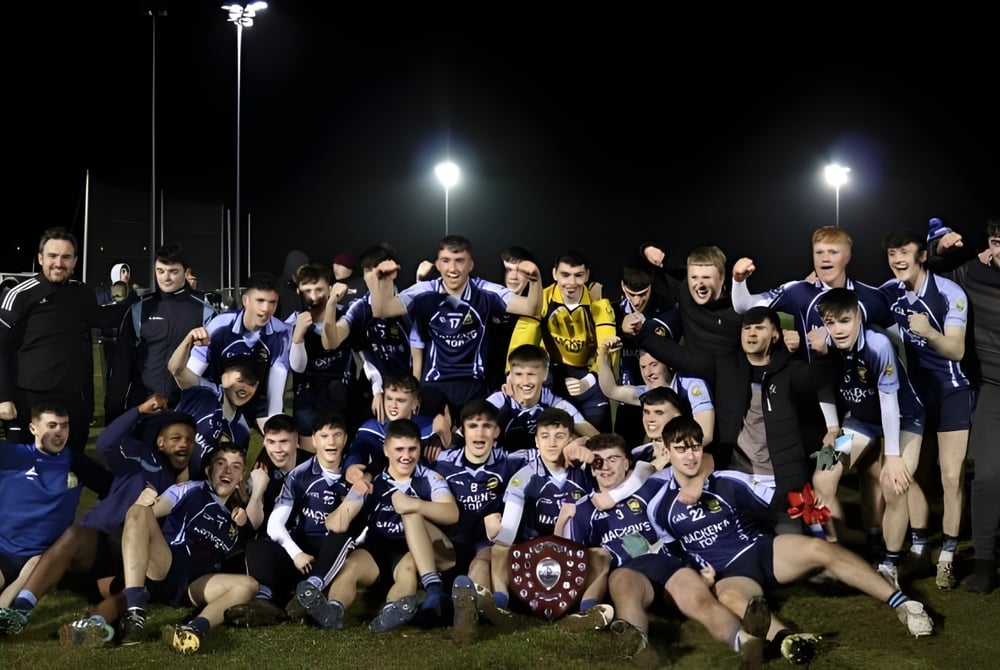 Die Sportmannschaft der Cnoc Mhuire Secondary School posiert gemeinsam auf dem Sportplatz bei Nacht.