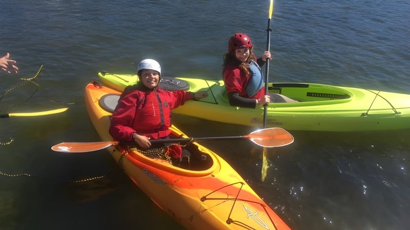 Zwei Personen paddeln in bunten Kajaks auf dem Wasser in der Nähe von Coalhurst High School.