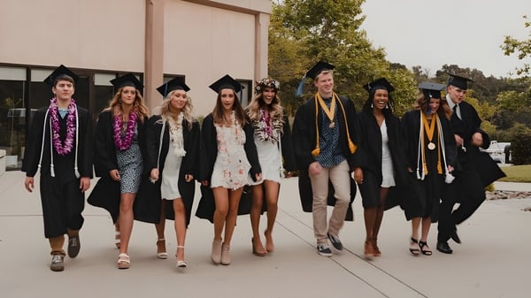Eine Gruppe von Absolventen steht in bunten Talaren vor einem Gebäude auf dem Campus der Coastal Christian School.
