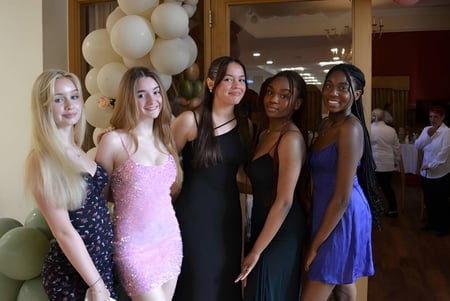Eine Gruppe junger Frauen in formeller Kleidung posiert vor Luftballons bei einer Feier an der Cobham Hall School.