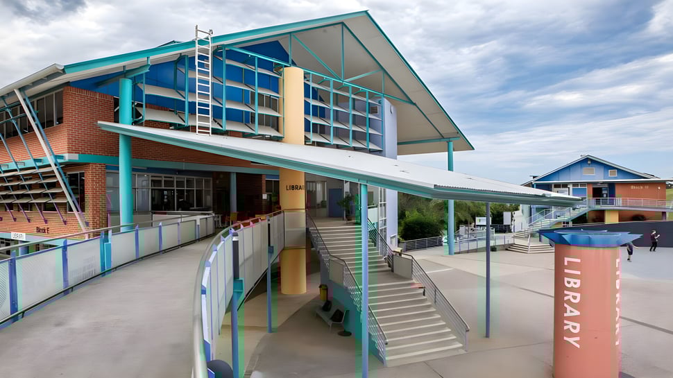 Das moderne Gebäude mit Eingang und Treppen des Coffs Harbour Senior College bei bewölktem Himmel.