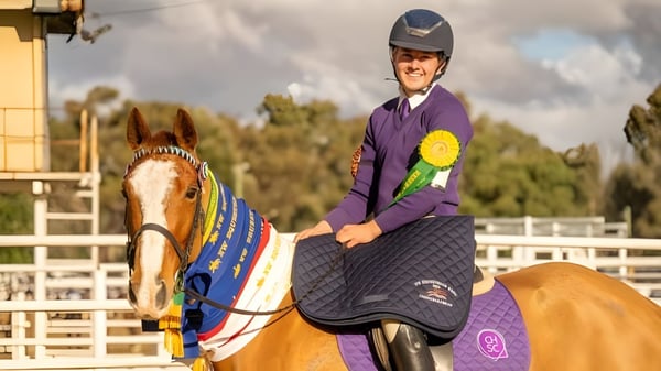 Eine Person in lila Uniform reitet ein bunt geschmücktes Pferd auf dem Gelände des Coffs Harbour Senior College.