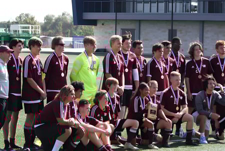 Eine Gruppe junger Fußballspielerinnen und Fußballspieler posiert gemeinsam auf dem Fußballfeld der Coláiste Bhaile Chláir.