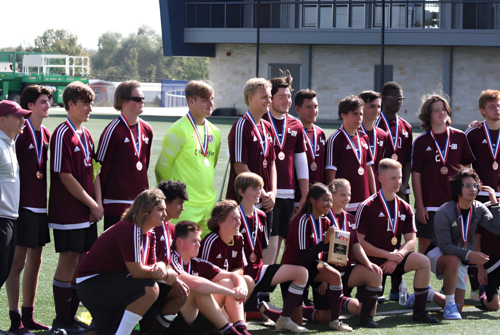 Eine Gruppe junger Fußballspielerinnen und Fußballspieler posiert gemeinsam auf dem Fußballfeld der Coláiste Bhaile Chláir.