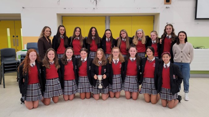 Eine Gruppe Schülerinnen in Schuluniformen steht gemeinsam in einem Klassenraum der Coláiste Bhaile Chláir.