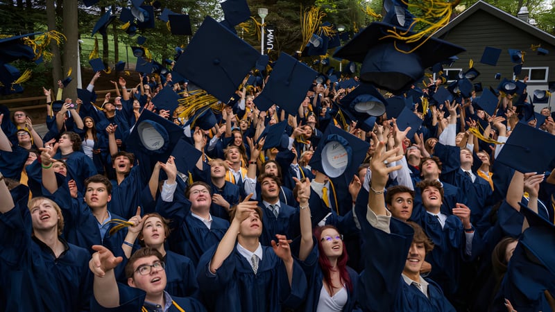 Absolventen in blauen Talaren feiern ihren Abschluss im Freien auf dem Campus der Colaiste Chiarain Athlone.
