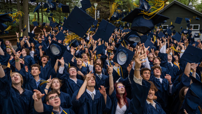 Absolventinnen und Absolventen der Colaiste Chiarain Athlone feiern draußen in ihren blauen Talaren ihren Abschluss.