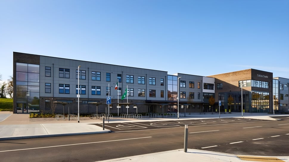 Das moderne mehrstöckige Gebäude der Colaiste Chiarain Athlone mit Glasfassaden und Parkplatz vor blauem Himmel.