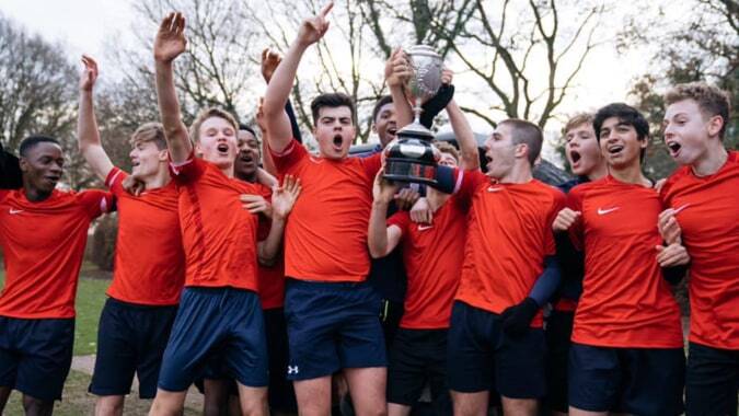 Schüler der Coláiste Chill Mhantáin feiern gemeinsam auf dem Fußballfeld im Freien.