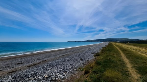 Eine Küstenlandschaft mit Kieselstrand und grasbewachsenem Weg nahe Coláiste Chill Mhantáin.