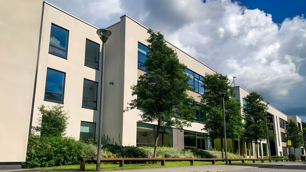 Das moderne mehrstöckige Gebäude mit großen Fenstern der Coláiste Choilm ist von Grünflächen umgeben.