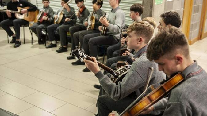 Eine Gruppe von Schülern musiziert mit Gitarren und Geigen in einer Unterrichtssituation auf dem Campus der Coláiste Choilm.