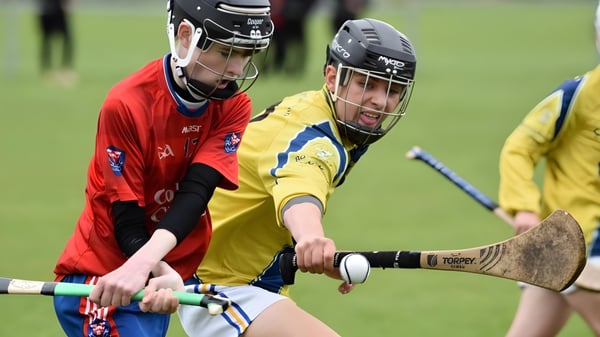 Zwei junge Athleten in Sportuniformen absolvieren einen Wettkampf auf dem Sportfeld der Coláiste Choilm.