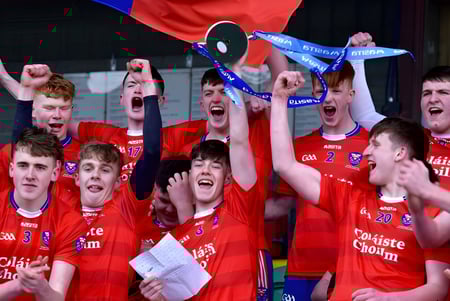 Eine Gruppe Schüler der Coláiste Choilm feiert mit einem gehaltenen Pokal ihren Sieg.