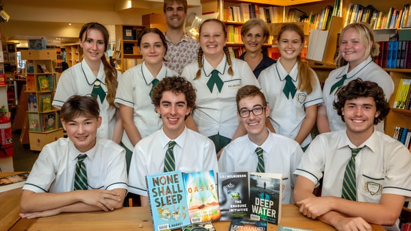 Eine Gruppe von Schülern der Coláiste Chríost Rí posiert gemeinsam in einem Buchladen und hält verschiedene Bücher.