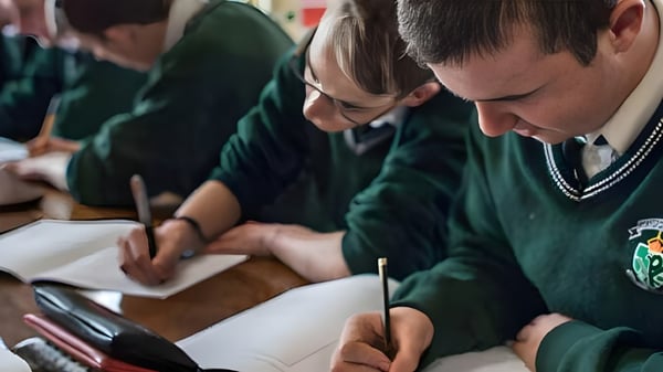 Schüler in Schuluniformen sitzen konzentriert an ihren Tischen im Unterricht der Coláiste Chríost Rí.