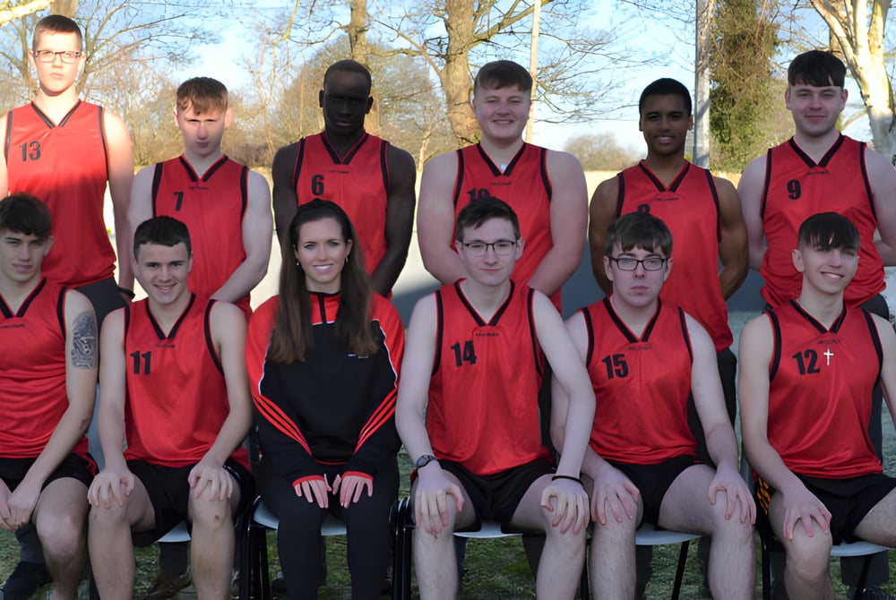 Eine Gruppe von Schülern der Coláiste Éamann Rís posiert im Freien für ein Mannschaftsfoto vor Bäumen und Gras.