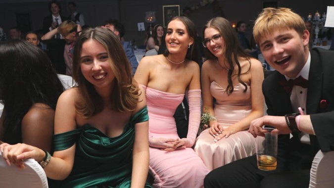 Eine Gruppe junger Frauen in formeller Kleidung posiert bei einer Veranstaltung am Coláiste Íosagáin.