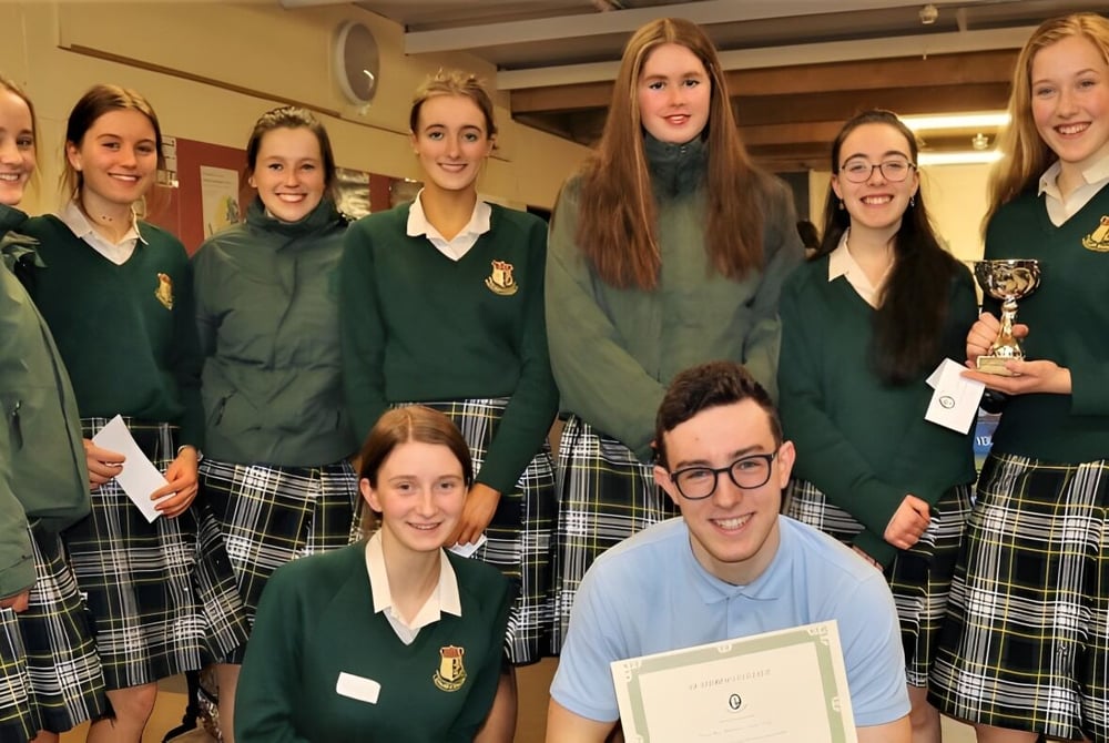 Eine Gruppe Schülerinnen der Coláiste Íosagáin posiert gemeinsam mit einer Trophäe in der Schule.