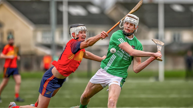 Zwei Spieler in Sportuniformen kämpfen auf dem Spielfeld auf dem Campus der Coláiste Íosagáin.