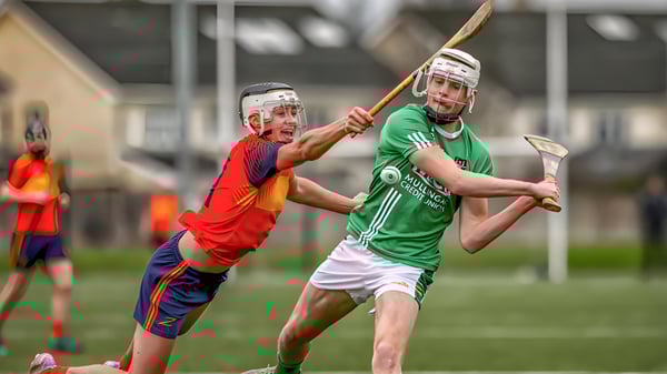 Zwei Sportler in Uniformen führen auf dem Spielfeld der Coláiste Íosagáin eine körperliche Auseinandersetzung aus.