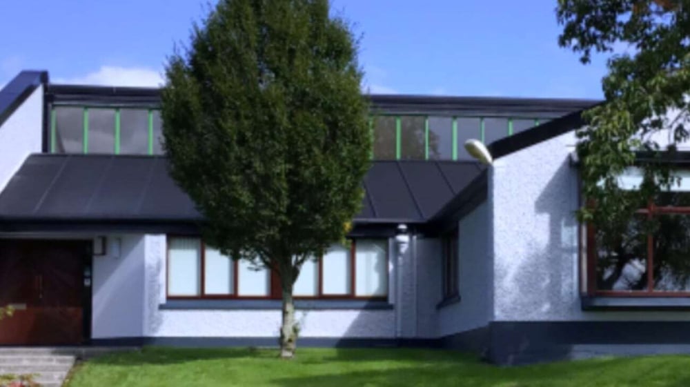 Ein modernes zweistöckiges Haus mit weißen Wänden und großen Fenstern vor einem Zypressenbaum auf dem Campus der Coláiste Mhuire Ballymote.