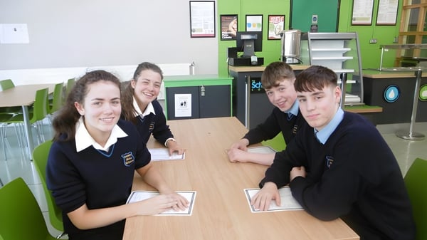 Schüler der Coláiste Mhuire Ballymote sitzen in Schuluniformen an einem Tisch im Klassenzimmer.