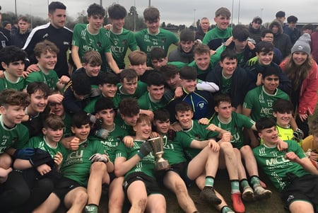 Eine große Gruppe junger Fußballspielerinnen und Spieler in grünen Trikots posiert auf dem Fußballfeld der Coláiste Mhuire Mullingar.