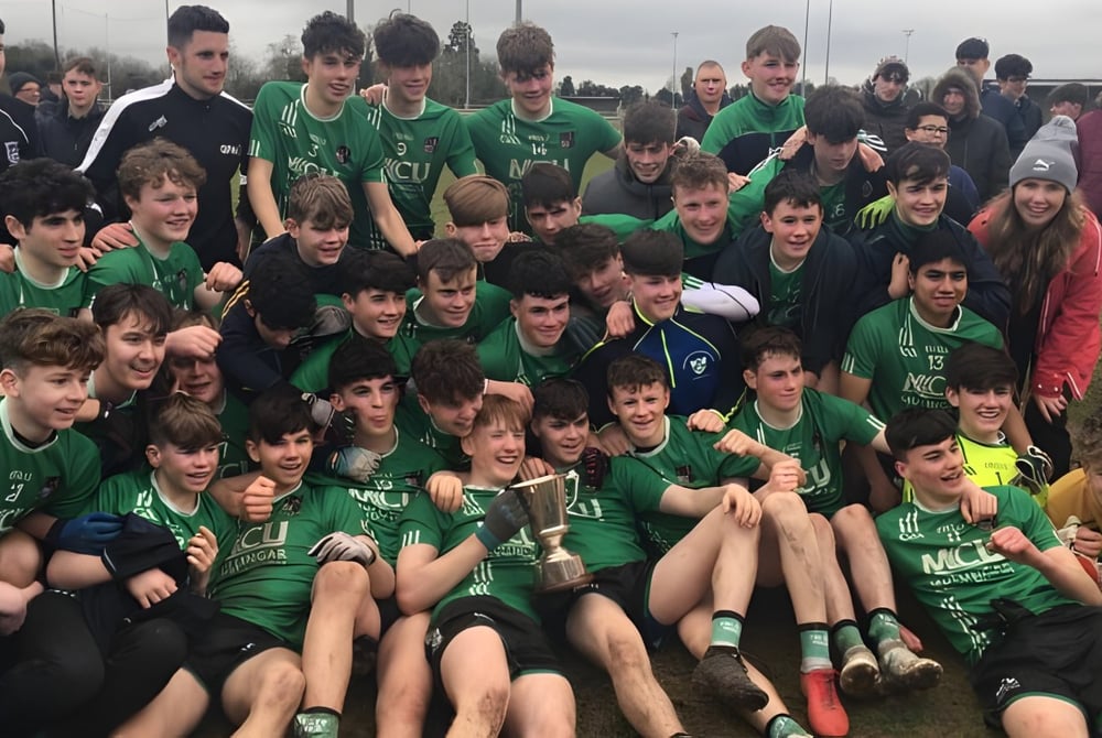 Eine große Gruppe junger Fußballspielerinnen und Spieler in grünen Trikots posiert auf dem Fußballfeld der Coláiste Mhuire Mullingar.