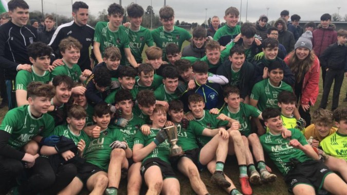 Eine Gruppe junger Fußballspielerinnen und Fußballspieler posiert in grünen und schwarzen Trikots auf dem Spielfeld der Coláiste Mhuire Mullingar.