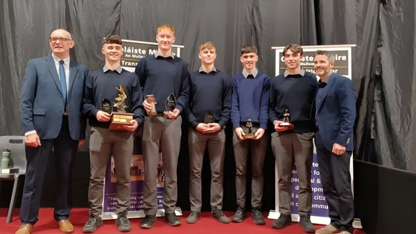 Eine Gruppe von Personen in formeller Kleidung steht auf der Bühne der Coláiste Mhuire Mullingar.