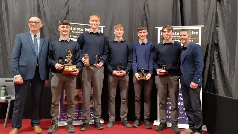 Eine Gruppe von Personen in formeller Kleidung steht auf der Bühne der Coláiste Mhuire Mullingar.