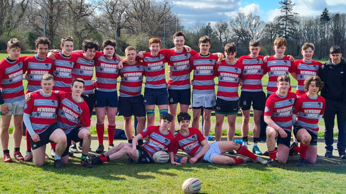 Schüler der Coláiste Mhuire Mullingar versammeln sich auf einer Wiese unter bewölktem Himmel.