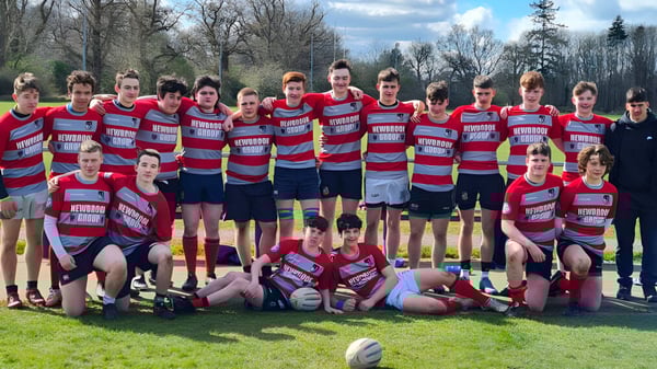 Eine Gruppe junger Sportler in roten und blauen Trikots steht auf dem Sportplatz der Coláiste Mhuire Mullingar.