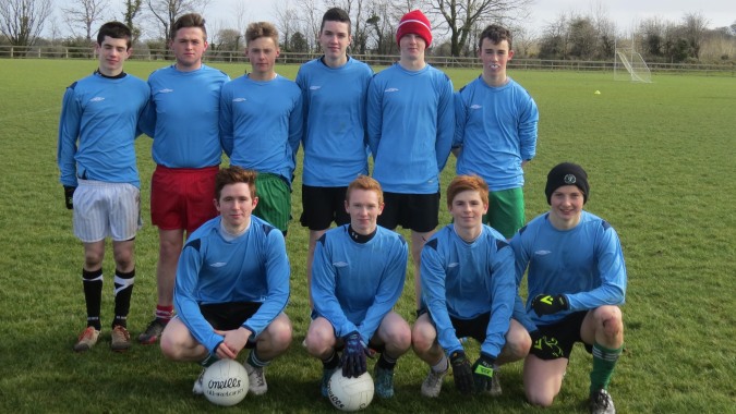 Eine Gruppe von Fußballspielern posiert auf dem Rasenfeld mit einem Ball im Vordergrund auf dem Campus der Coláiste Mhuire Ballymote.