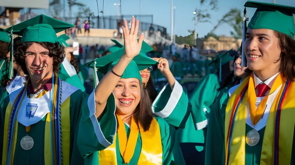 Eine Gruppe von Absolventen in grünen und gelben Talaren auf dem Campus der Coláiste Naomh Cormac.
