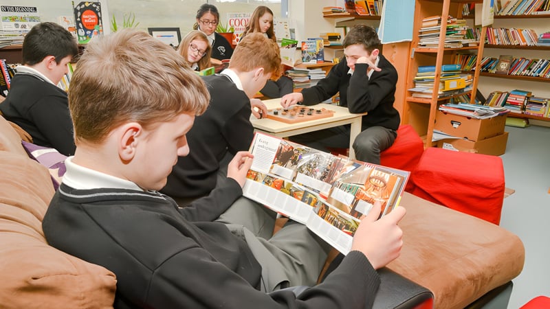Schüler der Coláiste Pobail Acla untersuchen gemeinsam Fotos und Dokumente an einem Tisch.