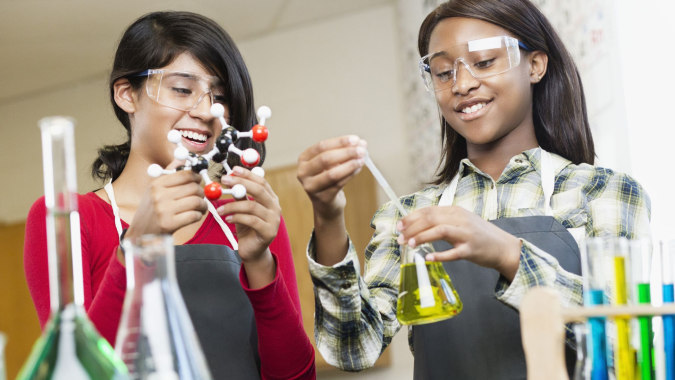 Zwei Schülerinnen führen in einem Klassenraum des Coláiste Pobail Acla ein naturwissenschaftliches Experiment mit verschiedenen Laborgeräten durch.