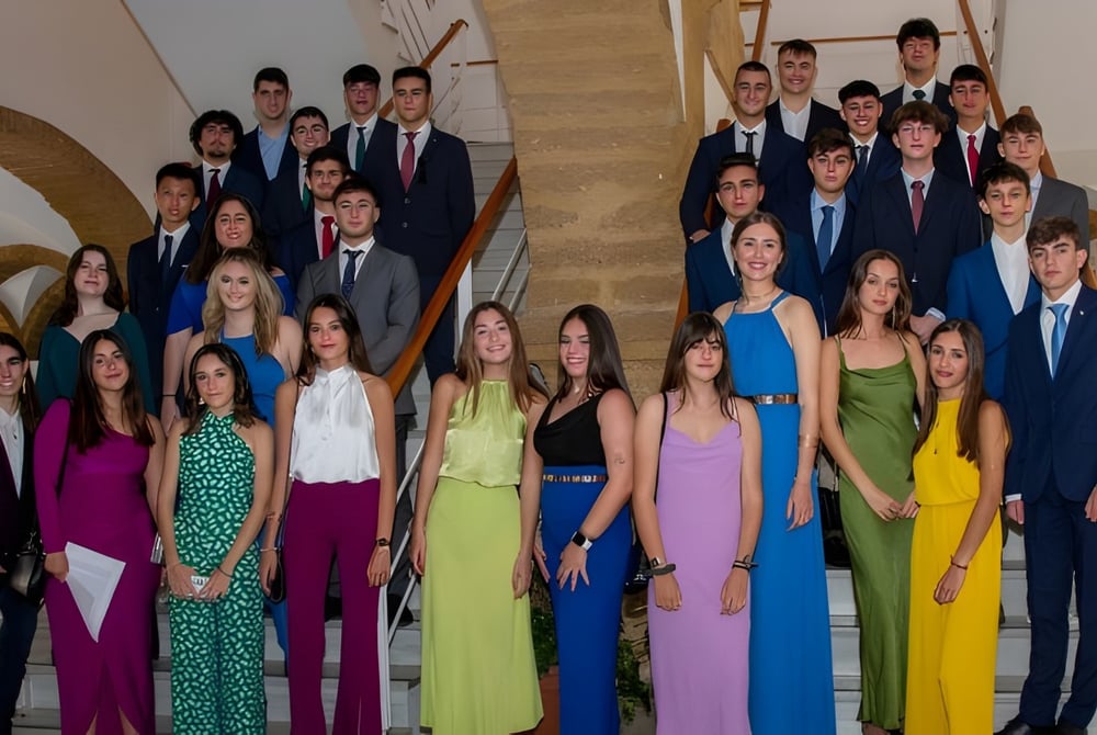 Eine Gruppe förmlich gekleideter Schülerinnen und Schüler steht gemeinsam in einem verzierten architektonischen Umfeld auf dem Campus des Colegio Argantonio.