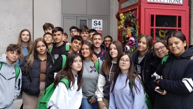 Eine Gruppe Schüler in grünen und weißen Uniformen steht vor einer roten Telefonzelle auf dem Schulgelände des Colegio Argantonio.