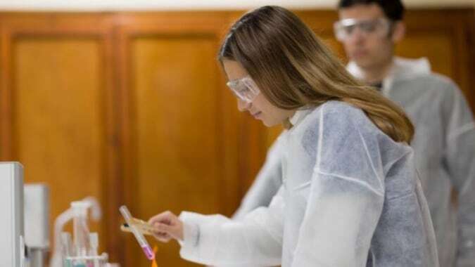 Eine Frau in weißem Kleid steht in einem Raum mit Holzwänden auf dem Campus der Colegio Esclavas.